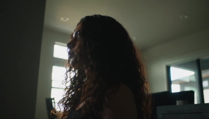 A woman with long hair and eyes closed in a room
