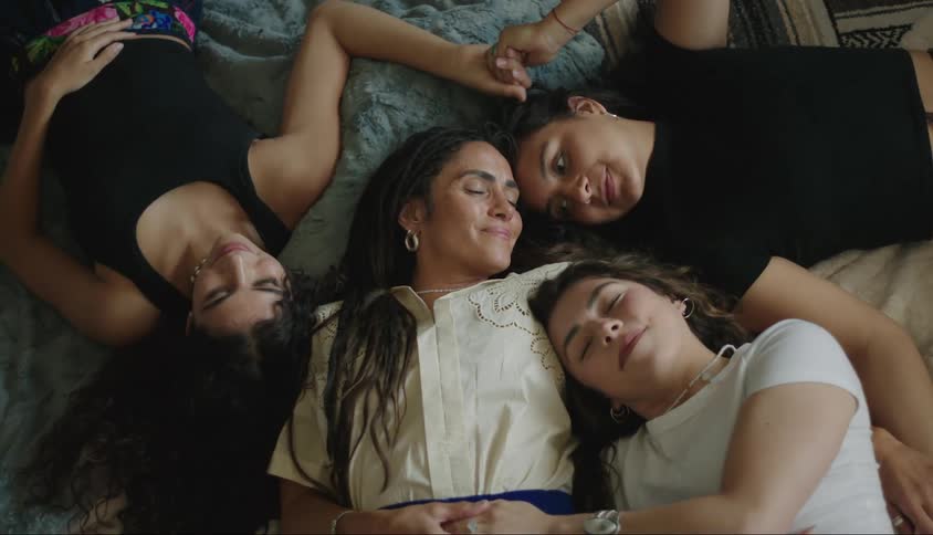 Woman happily cuddles with younger women while they all lie down