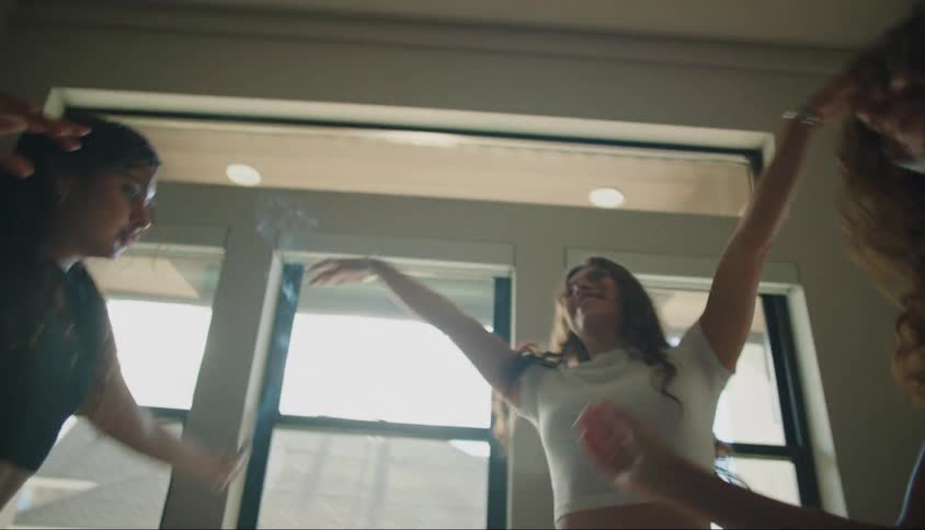 Three young girl friends dancing together in a room