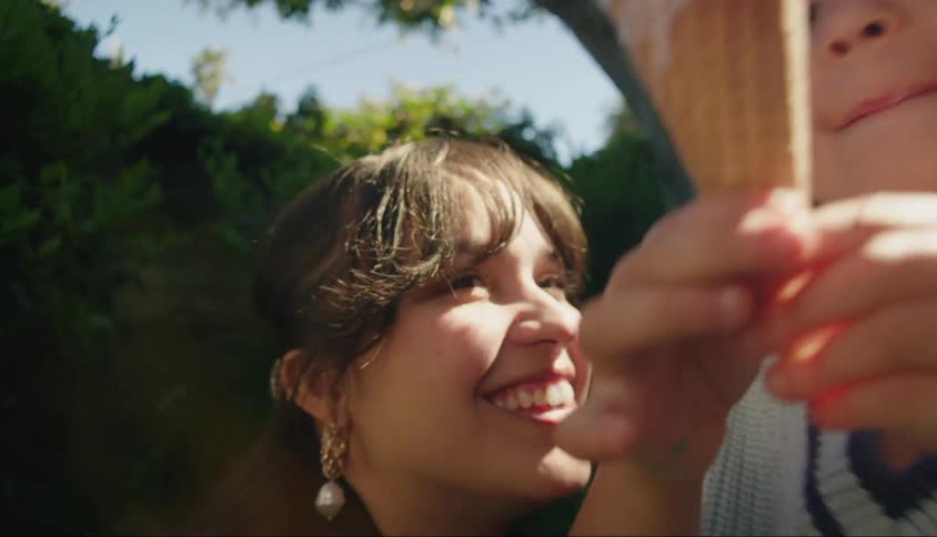 Smiling woman watching a little girl sucking ice cream outdoors