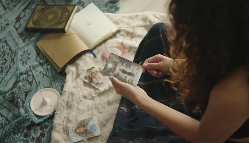 A woman looks at various items arrayed on a blanket such as cards and a book