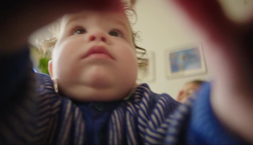 A toddler grabs at a camera in a living room