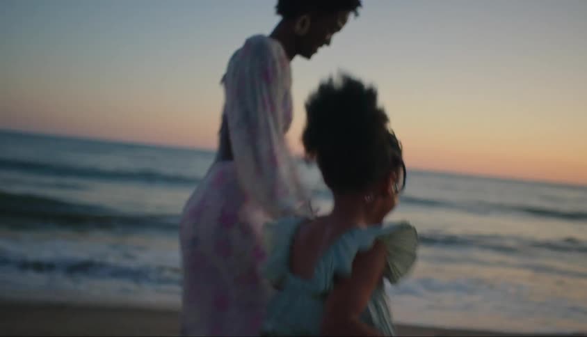 A mother and daughter have fun running along a beach