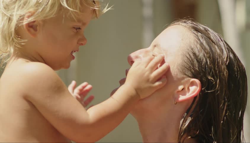 Little boy playfully slapping his mothers face
