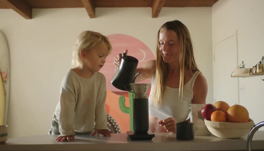 Mother in the kitchen preparing coffee together with her little son