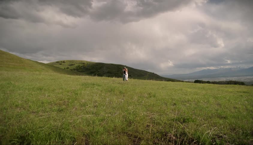 Couple consisting of a man and a woman walking in a field on a cloudy day