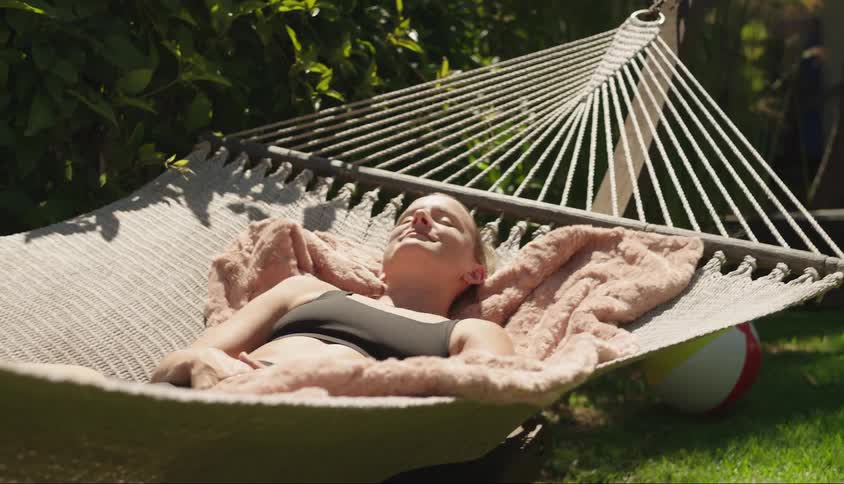 Woman lying in a hammock in a backyard