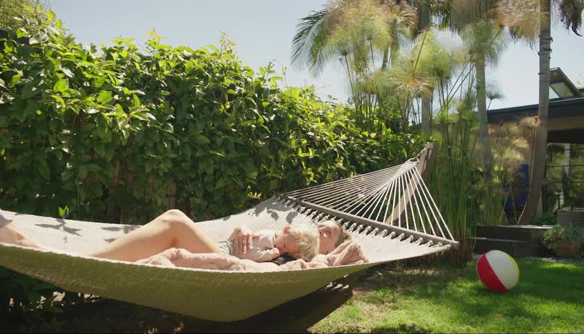 Mother lying in a hammock with her son in an openair backyard