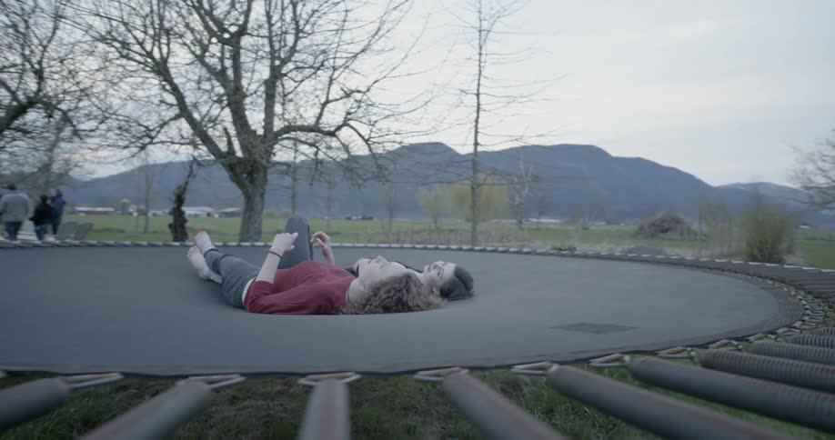 Two women lay on a trampoline during the day