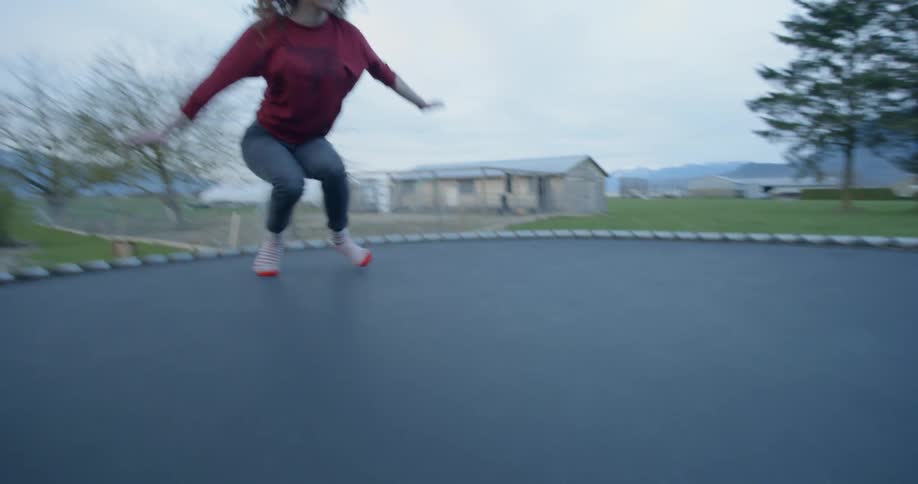 Woman performing a backflip on an outdoors trampoline on a fall day