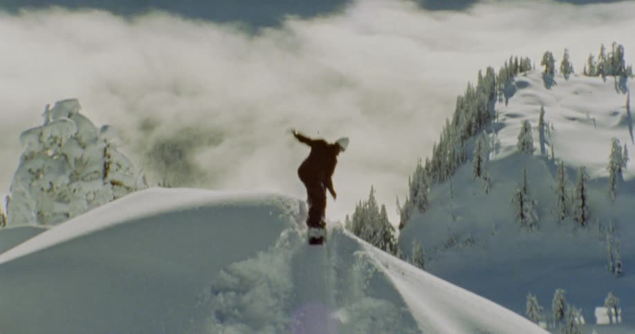 A person snowboarding in the snow to a slope and jumping