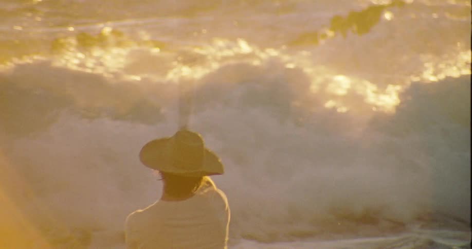 Man fishing in a rough sea under the golden light of dawn