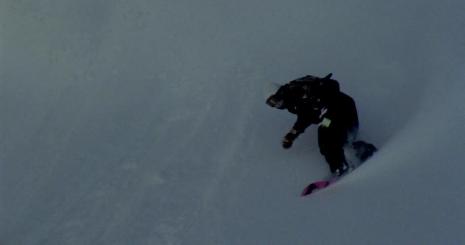 Person descending a mountain with snowboard maneuvers