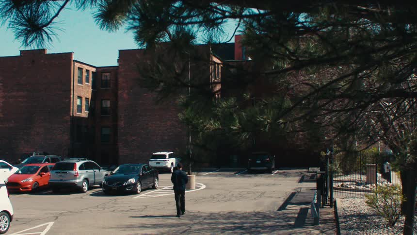 Man entering a parking lot throwing a bag of trash and then getting into his car