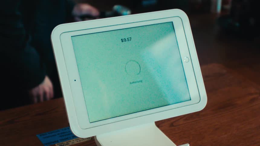 Persons hand processing a payment on a tablet screen in a store