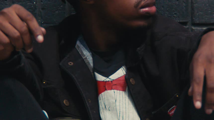 A man is sitting against the wall outside