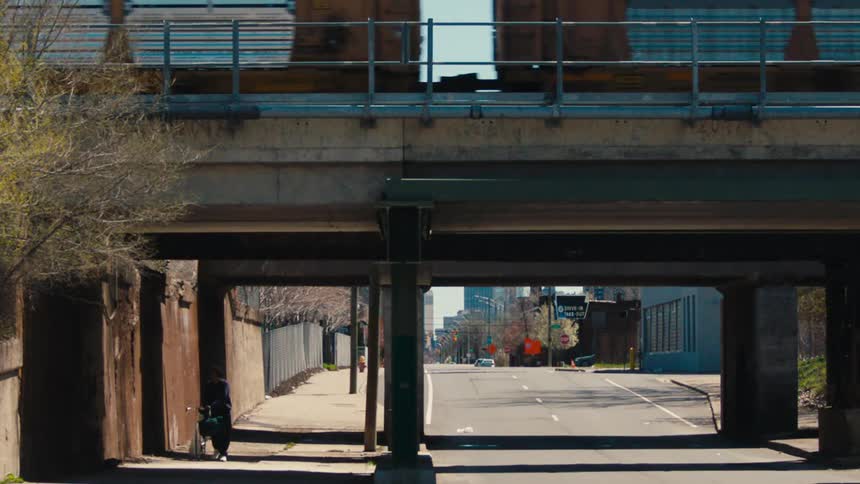 Person walks bike under bridge as train passes overhead