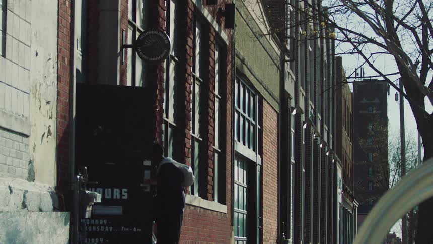 A man pushing his bicycle against the wall of a building and then opening a door