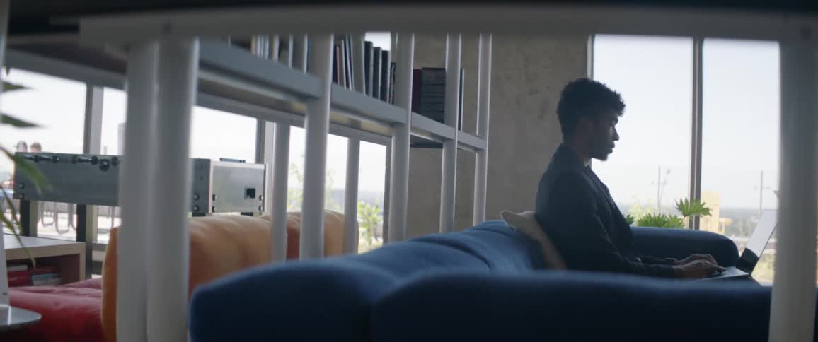Man sitting on a blue sofa using a laptop