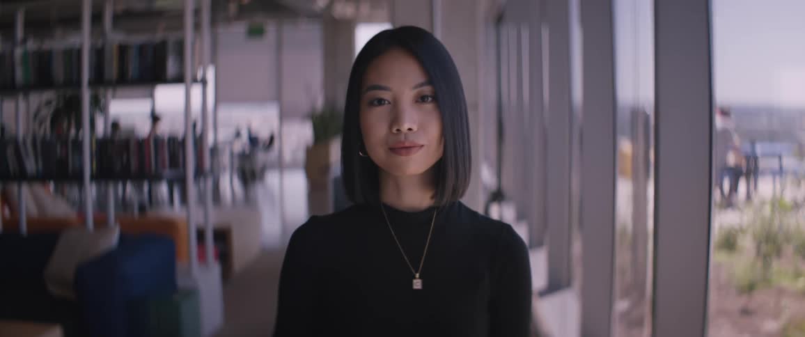 An asian woman standing in a library near large windows