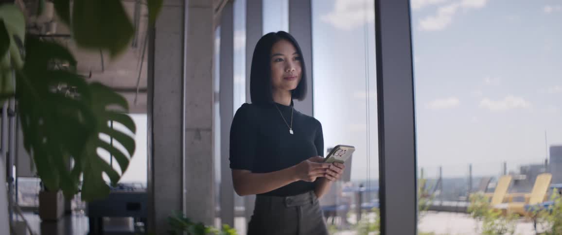 An asian smiles while scrolling through her smartphone
