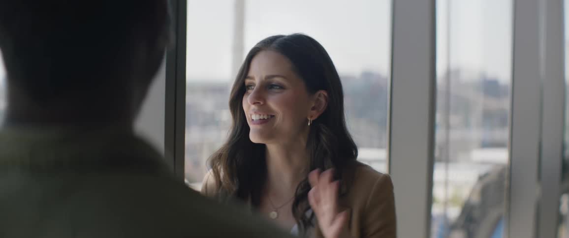 Coworkers talk in the office by the large window