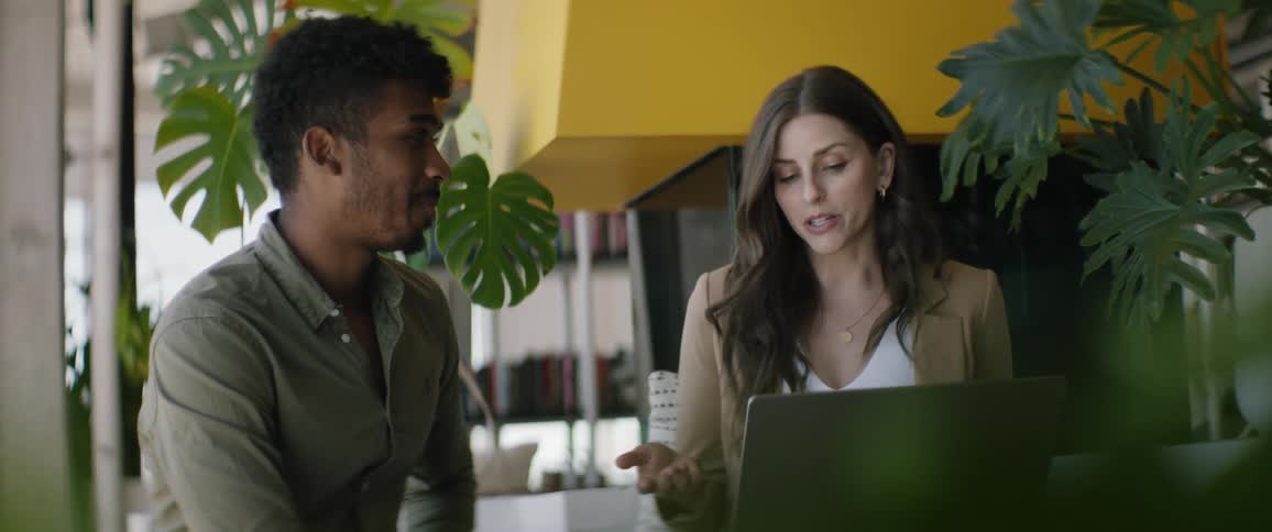 Two people sitting and talking with a laptop open in front of them