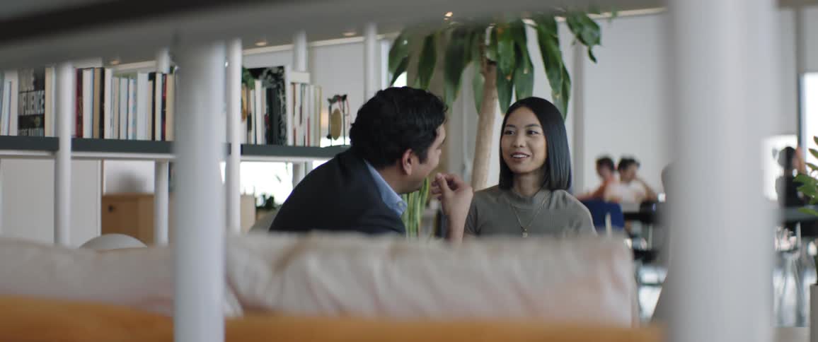 Two people sitting in a workplace talking