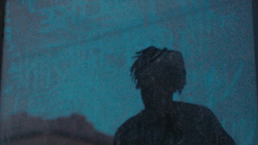 Man pauses to check himself out in grimy window as light rail passes in the background