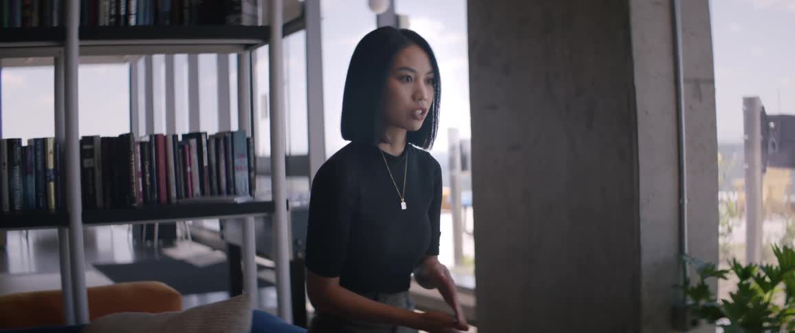 An asian woman speaking while standing in a library