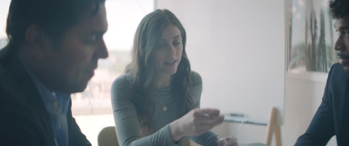 Three people sitting at a table talking in a meeting with documents