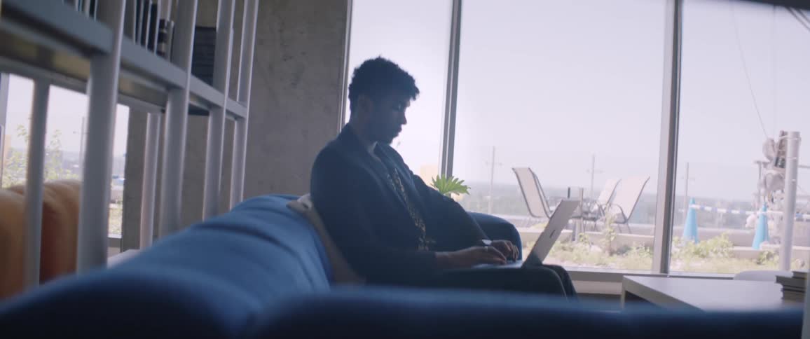 Man sitting in an armchair concentrated while typing on his laptop