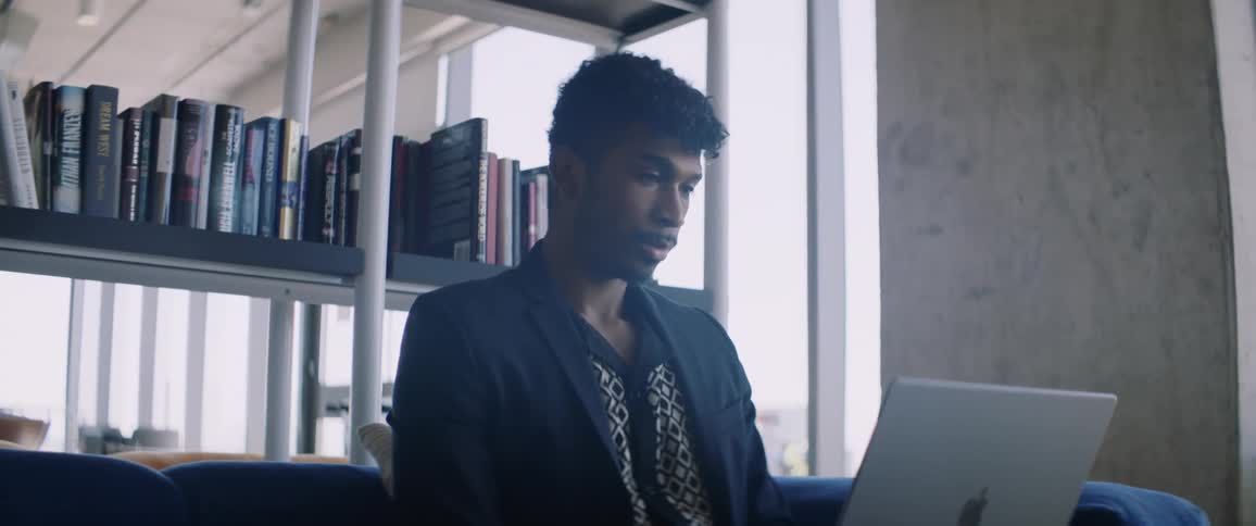 A man uses a laptop while sitting in a library