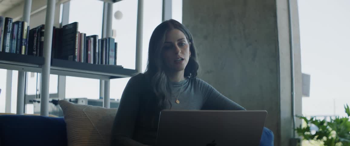 A woman is talking and typing with her laptop