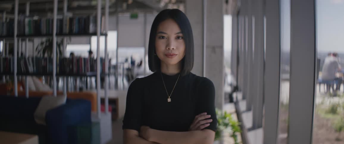 Young short black haired woman crossing her arms while working indoors