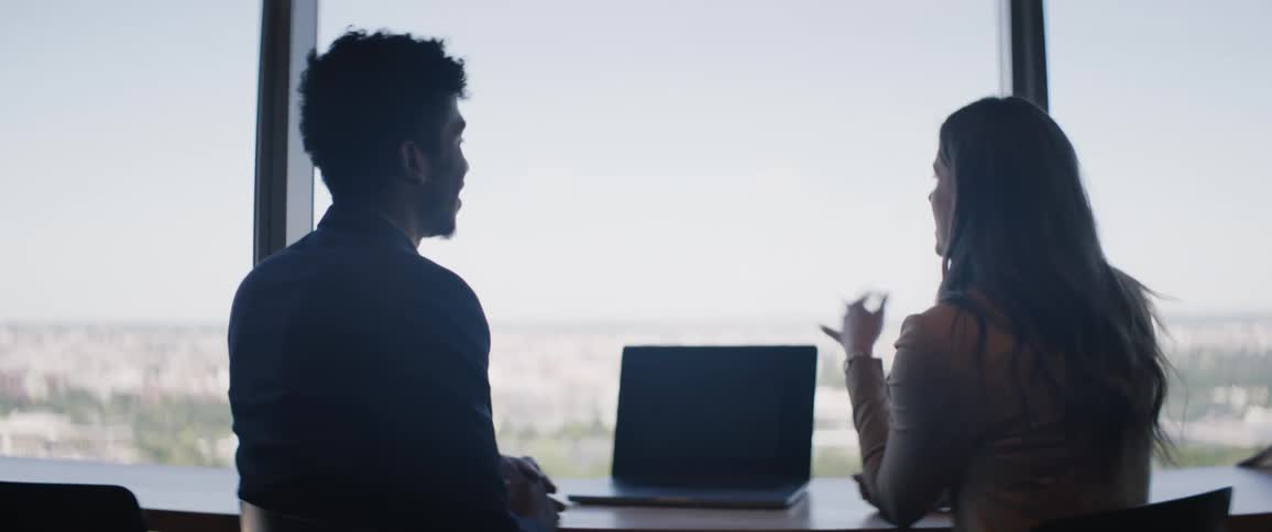 A man and a woman sit in an office and have a discussion