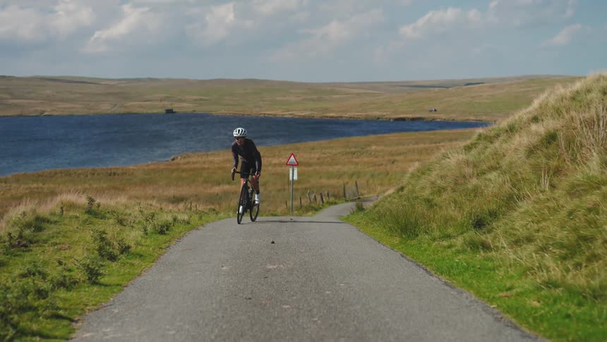 A woman on racing bike puts in effort up a steep hill