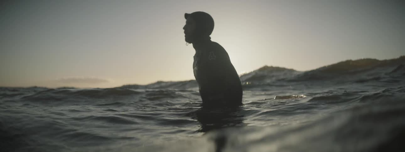 Person sitting on a floating device as seen from a water level view at sunset