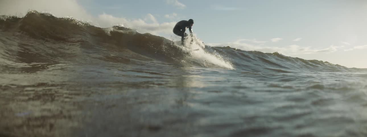 A surfer catches a wave during the day