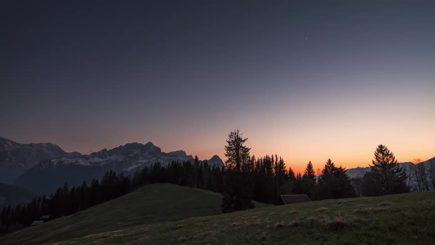 Time lapse of a sunset over a mountainous landscape turning into a starry night