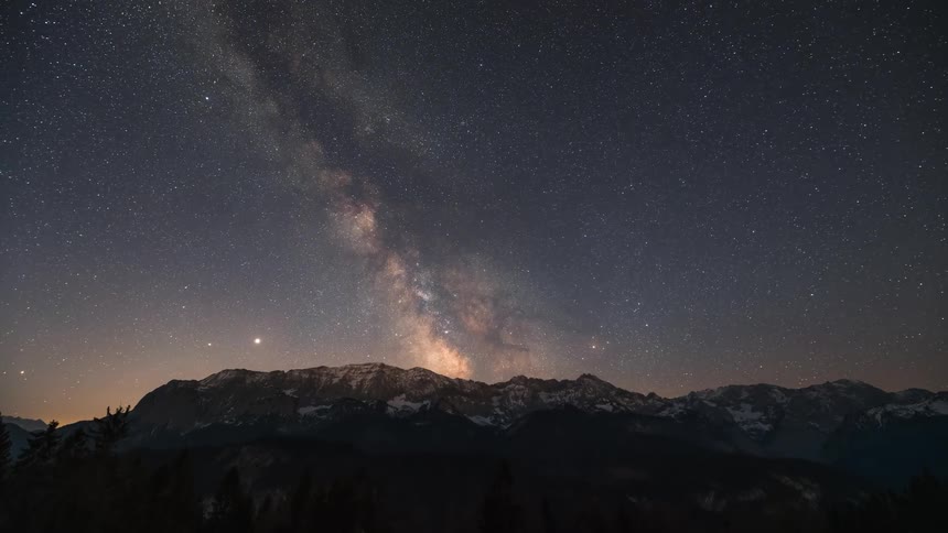 Time lapse of the milky way moving over snowcapped mountains until sunrise