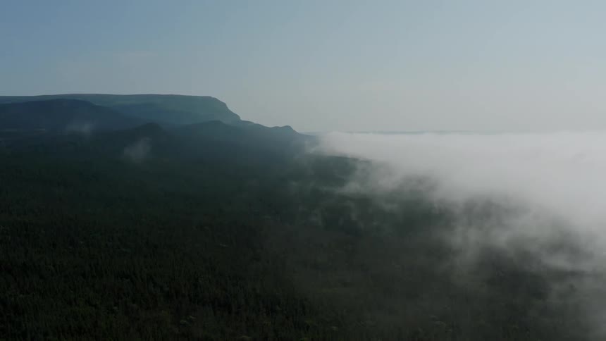 Thick clouds roll into a mountainous coast