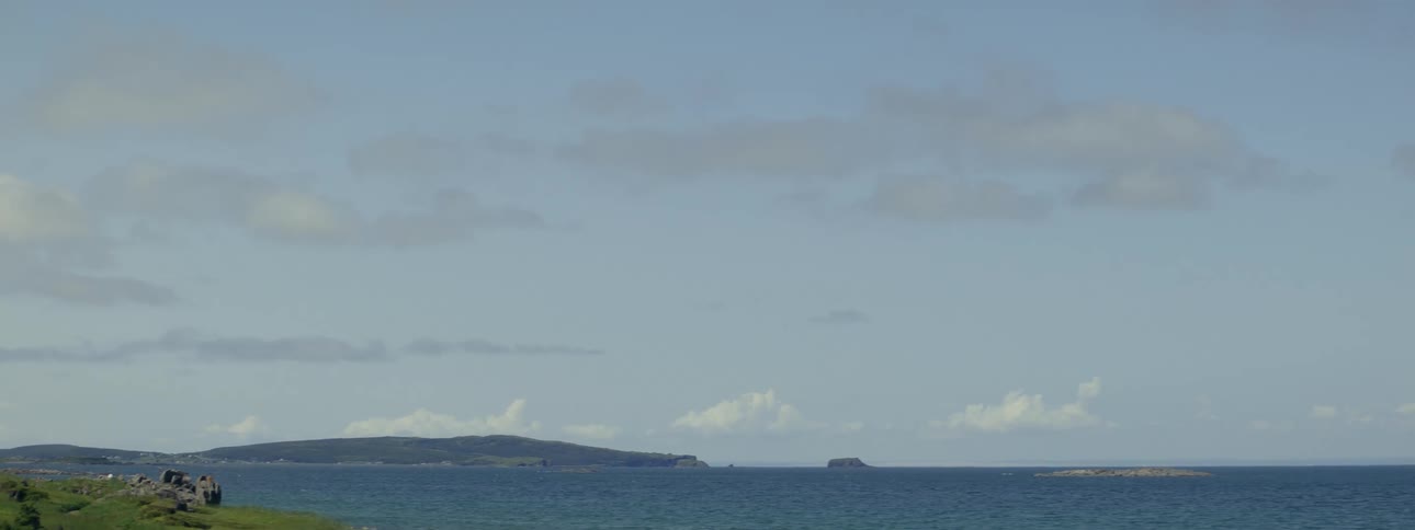 Rock formation and gray rocks stand on shore on a cloudy day