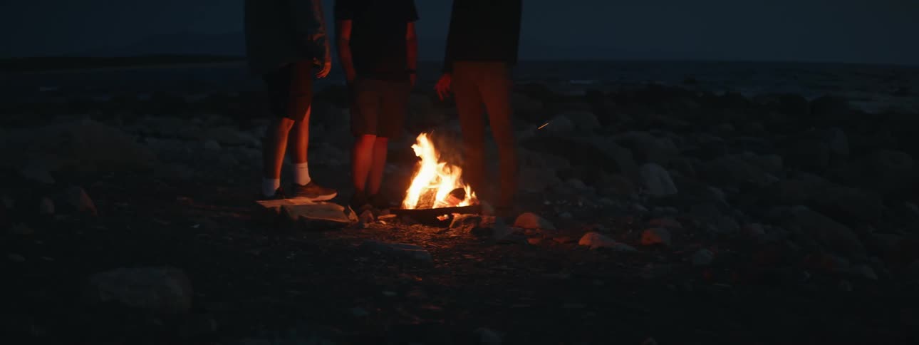 People gather around a small campfire in nature at night