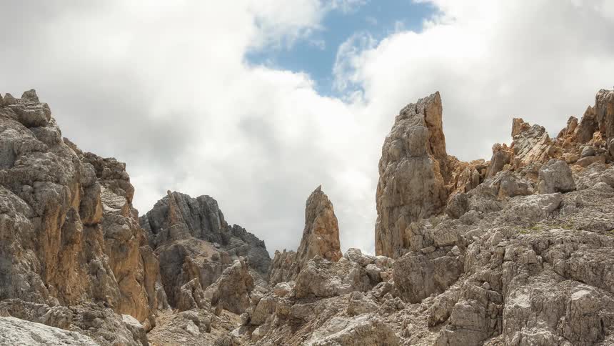 Some rock formations and there are white clouds passing quickly in the sky