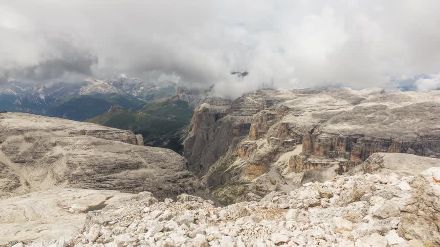 Time lapse of clouds rolling over a rugged mountain landscape with layered rock formations