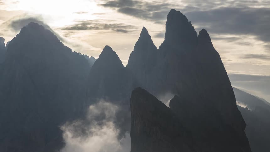 Clouds move above and against a tall mountain range