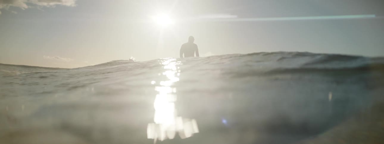 A man stands up on his surf board while riding a wave