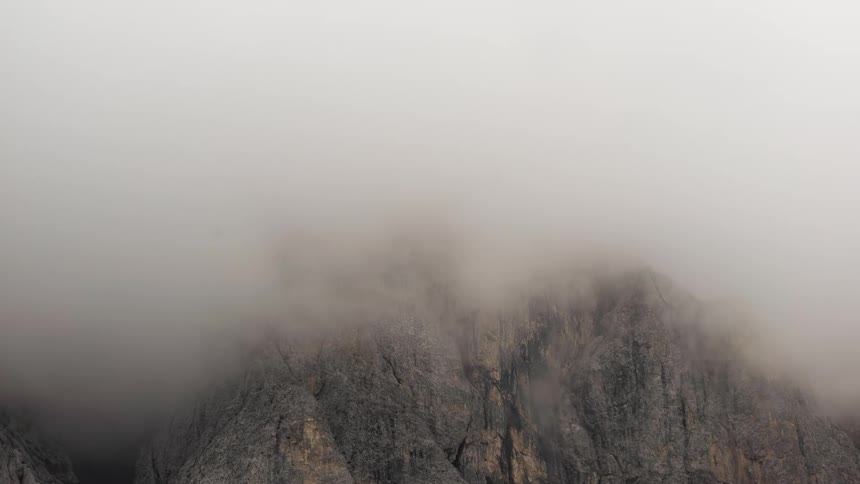 Rocky mountain with clouds and fog passing by