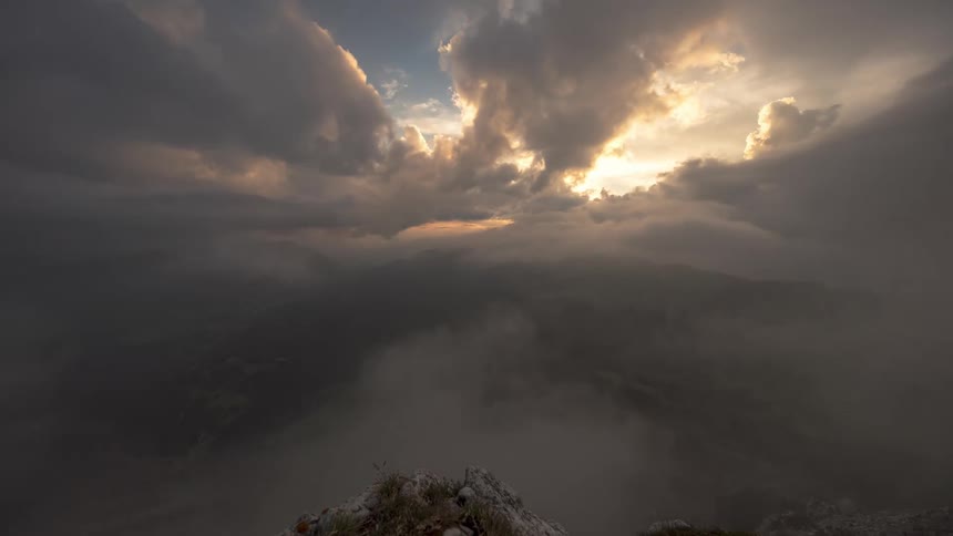 Mountainous landscape seen from a high point with dramatic clouds and sun rays